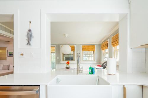 a white kitchen with white counters and a sink at Hip Island House in Charleston