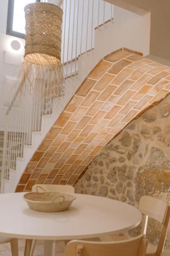 a room with a table and a staircase with a stone wall at La Vila Hort by Seaward Suites in Villajoyosa