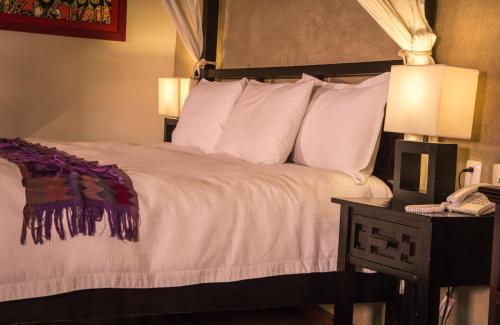a bedroom with a bed with white sheets and a phone at Guayaba Inn Boutique Hotel in San Cristóbal de Las Casas