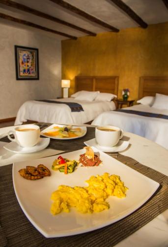 a table with a plate of food and two beds at Guayaba Inn Boutique Hotel in San Cristóbal de Las Casas
