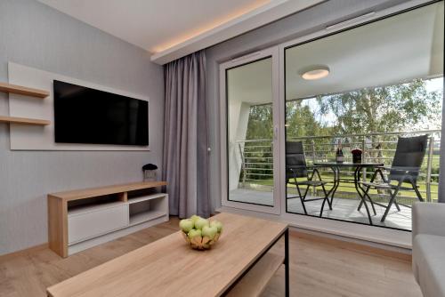a living room with a large sliding glass door with a television at BlueApart Apartamenty Na Klifie in Władysławowo