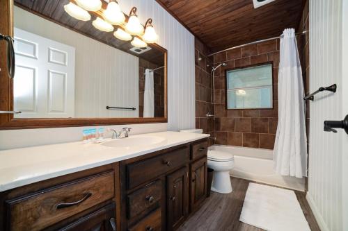 ein Badezimmer mit Waschbecken, Toilette und Spiegel in der Unterkunft Charming Cottage With Pool Table 15 Min From WEC in Ocala