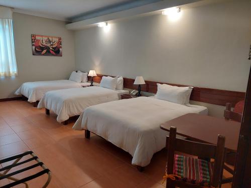 a hotel room with three beds with white sheets at Lima Wasi Hotel Miraflores in Lima