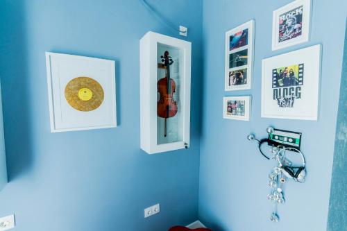 a room with a blue wall with pictures and a violin at Catharsis House - self check in and self checkout in Oradea