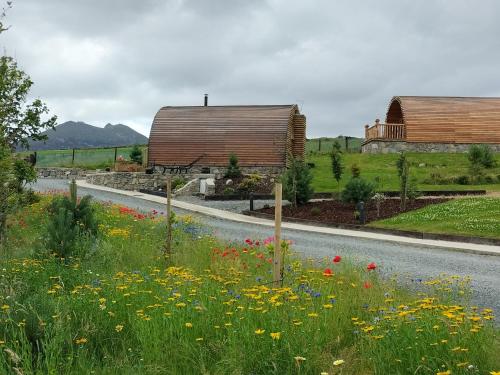 a road with a field of flowers and buildings at Tollymore Luxury log cabins in Newry