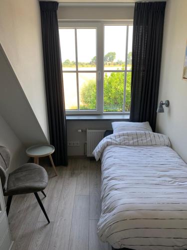 een slaapkamer met 2 bedden, een stoel en een raam bij Dijkhofje, dichtbij strand, zee en meer. in Vrouwenpolder