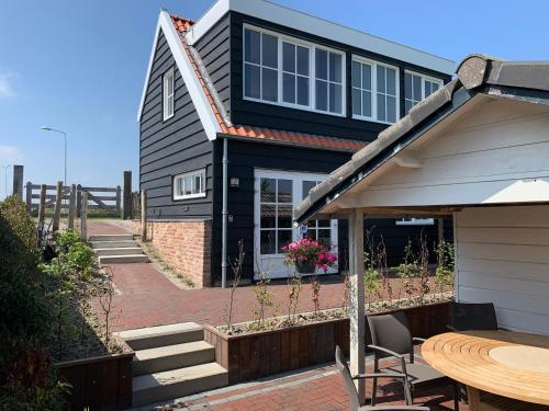 a black house with a patio and a table at Dijkhofje, dichtbij strand, zee en meer. in Vrouwenpolder