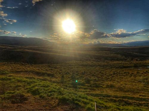a field with the sun in the sky at Beautiful cottage with Mountain View in Fludir