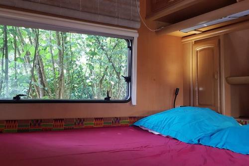 a bed in a room with a large window at L'hermitage d'Apollon au sein d'un jardin forêt près de l'océan in Mimizan