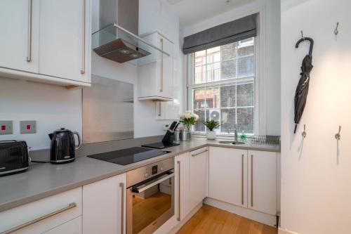 a kitchen with white cabinets and a window at GuestReady - Stunning Covent Garden 2BR Duplex in London