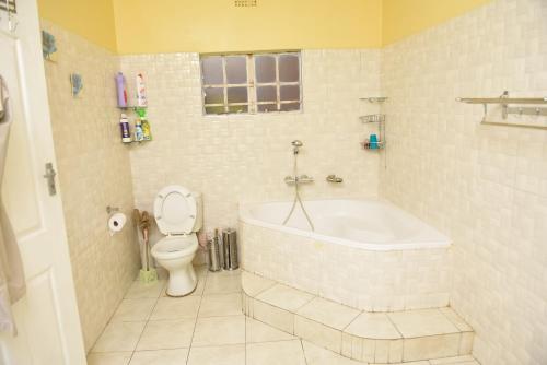 a bathroom with a bath tub and a toilet at AZB Cozy Homes. Elegant 4 bedroom home in Area 49, Lilongwe in Lilongwe