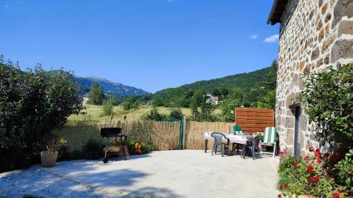 un patio con mesa, sillas y una valla en La basse-cour, en Vic-sur-Cère