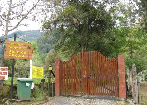 a wooden gate with a sign next to a tree at Casa Campo Valle De Cocora in Salento