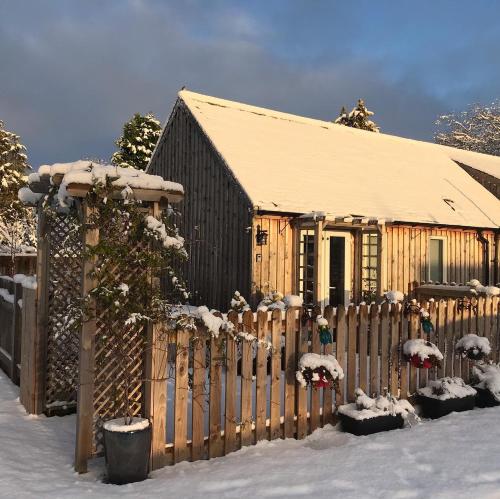 a wooden fence in front of a house covered in snow at Courtyard Bothy in Grantown on Spey