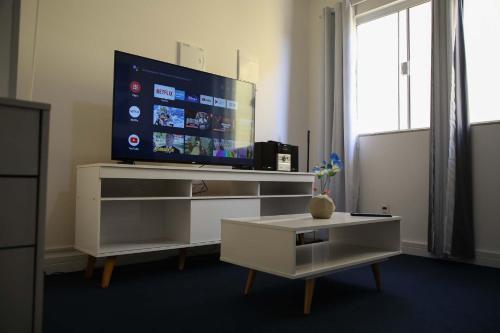 a living room with a tv and a white entertainment center at Elegante Duplex Oceanico da Elena Super Cozinha USP y UfSCAR in São Carlos