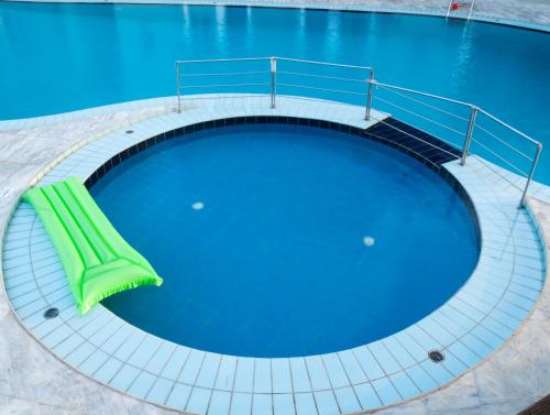 a large swimming pool with a green bench next to it at Casa Maria Hotel Apts in Platanias