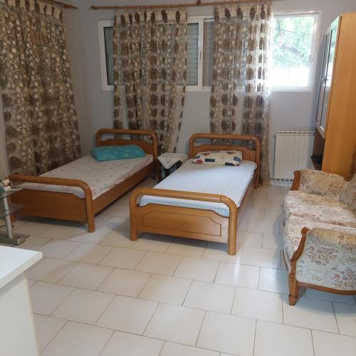 a room with three beds and a couch and a window at Γκρι βιλλα 2 in Periyiálion