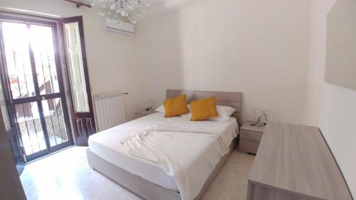 a white bedroom with a bed with two yellow pillows at Da Lina e Rosetta in Acireale