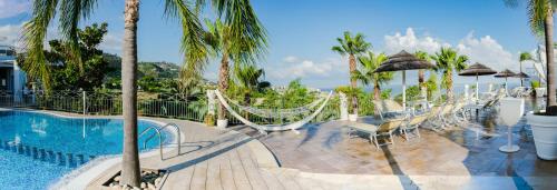 a resort swimming pool with hammocks and palm trees at Residence Porto Ulisse in Parghelia