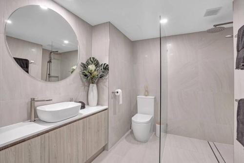 a bathroom with a sink and a toilet and a mirror at Panoramic Ocean View 2 bed 2 bath in Alexandra Headland
