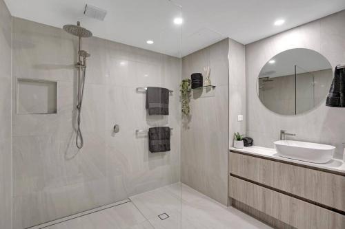 a bathroom with a shower and a sink and a mirror at Panoramic Ocean View 2 bed 2 bath in Alexandra Headland