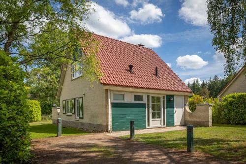 a white house with a green garage at Bungalow - 6 Persons in Hellendoorn