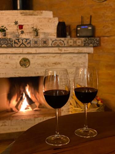 two glasses of wine sitting on a table in front of a fireplace at Chalé Som da Sete Quedas Hidromassagem, Lareira e Vista para as Montanhas in Gonçalves