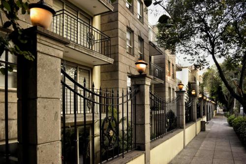 a building with a wrought iron fence next to a sidewalk at Suites Obelisk in Mexico City