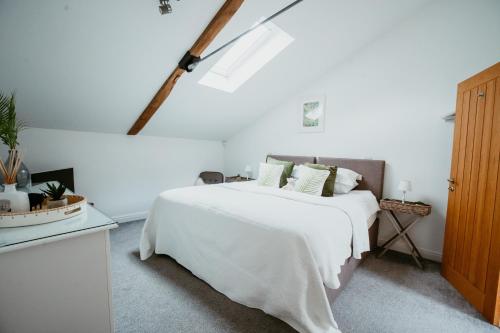 a white bedroom with a white bed and a window at The Clock Tower Stow in Stow on the Wold