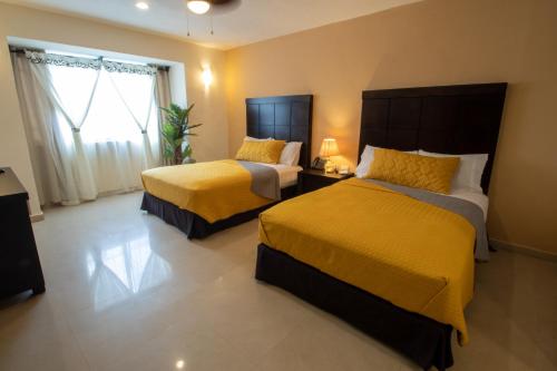 a hotel room with two beds and a window at Hotel Villas Segovia Playa del Carmen in Playa del Carmen
