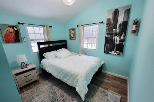 um quarto azul com uma cama e 2 janelas em NEW! Hurleyville Upstate NY - your Catskills getaway with hot tub, sauna and firepit! em Hurleyville