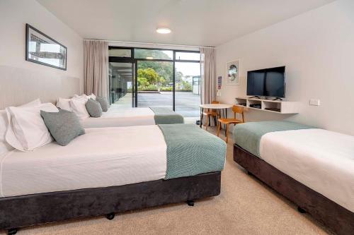 a hotel room with three beds and a flat screen tv at The Com Plex Motel in Whakatane