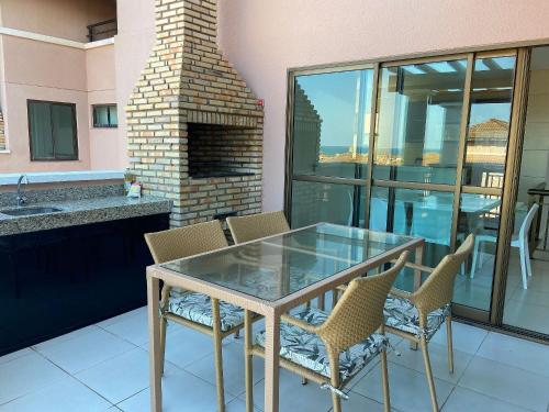 a glass table and chairs on a balcony with a fireplace at Apto. Beverlly Hills, Próx. Beach Park in Aquiraz
