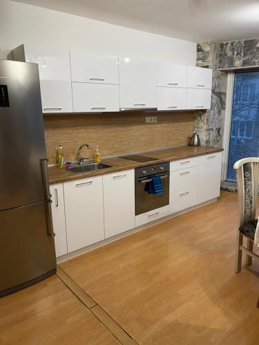 a kitchen with white cabinets and a stainless steel refrigerator at Spacious apartment on Main Street (City Center) in Kazanlŭk