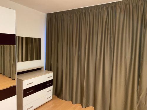 a bedroom with a curtain and a dresser and a mirror at Spacious apartment on Main Street (City Center) in Kazanlŭk