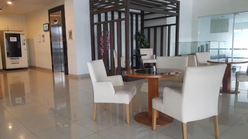 a dining room with a table and white chairs at Apartemen Newton Kayla in Bandung