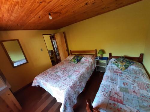 a bedroom with two beds and a wooden ceiling at Casa da Marinda in Visconde De Maua