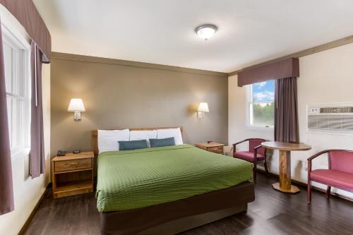 a hotel room with a green bed and two chairs at Malone Inn in Malone