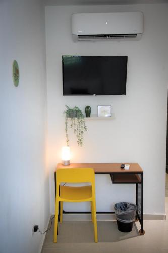 a desk with a yellow chair and a tv on a wall at Nomada Beach Hostel- Isla Verde in San Juan