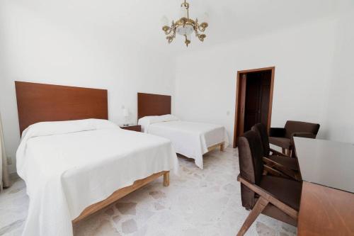 1 dormitorio con 2 camas, silla y lámpara de araña en Violeta Hotel Boutique, en Tepatitlán de Morelos