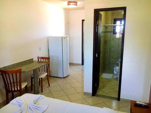 a kitchen with a table and a refrigerator in a room at Pousada Beija Flor in Natal