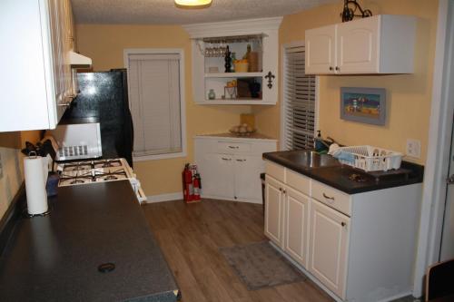 a kitchen with white cabinets and a black counter top at Key West Style Historic Home in Coconut Grove Florida The Yellow House in Miami