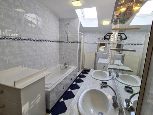 uma casa de banho branca com 2 lavatórios, uma banheira e um tubermott em Gîte Franconville, 3 pièces, 4 personnes - FR-1-584-181 