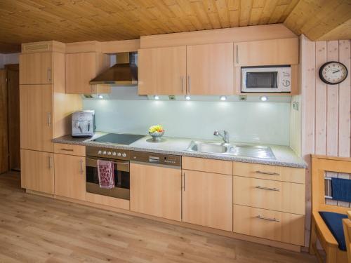 a kitchen with wooden cabinets and a sink and a microwave at Ferienwohnung Lerch in Bregenz