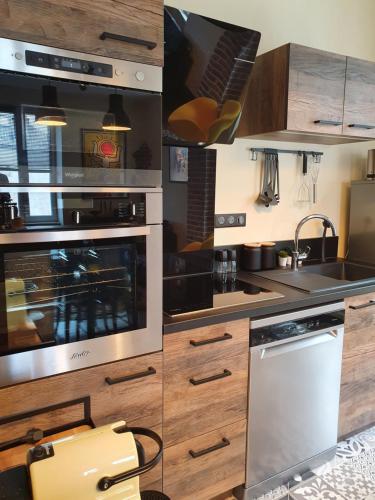 una cocina con electrodomésticos de acero inoxidable y armarios de madera en villa l'Ambroisine en Lure