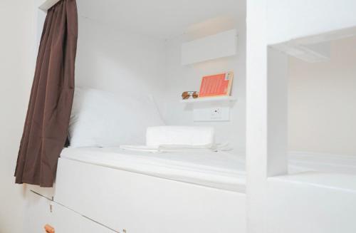 a room with white walls and a shelf with books at The A Hostel in Boracay