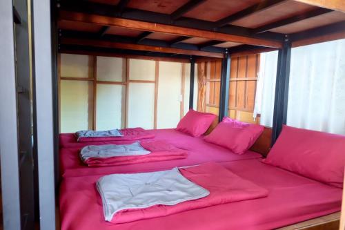 a room with four beds with pink sheets and pillows at Bankruchaem Homestay Kohpu in Ban Klang