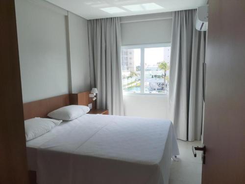 a bedroom with a white bed and a window at Exclusive Resort in Salinópolis