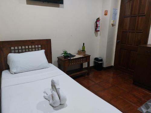 a bedroom with a bed with a pair of shoes on it at Makabata Guesthouse & Cafe in Manila