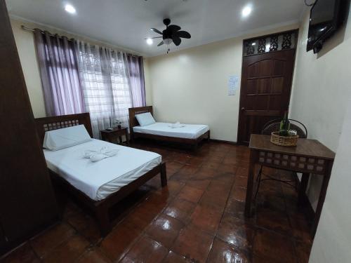 a room with two beds and a chair and a table at Makabata Guesthouse & Cafe in Manila